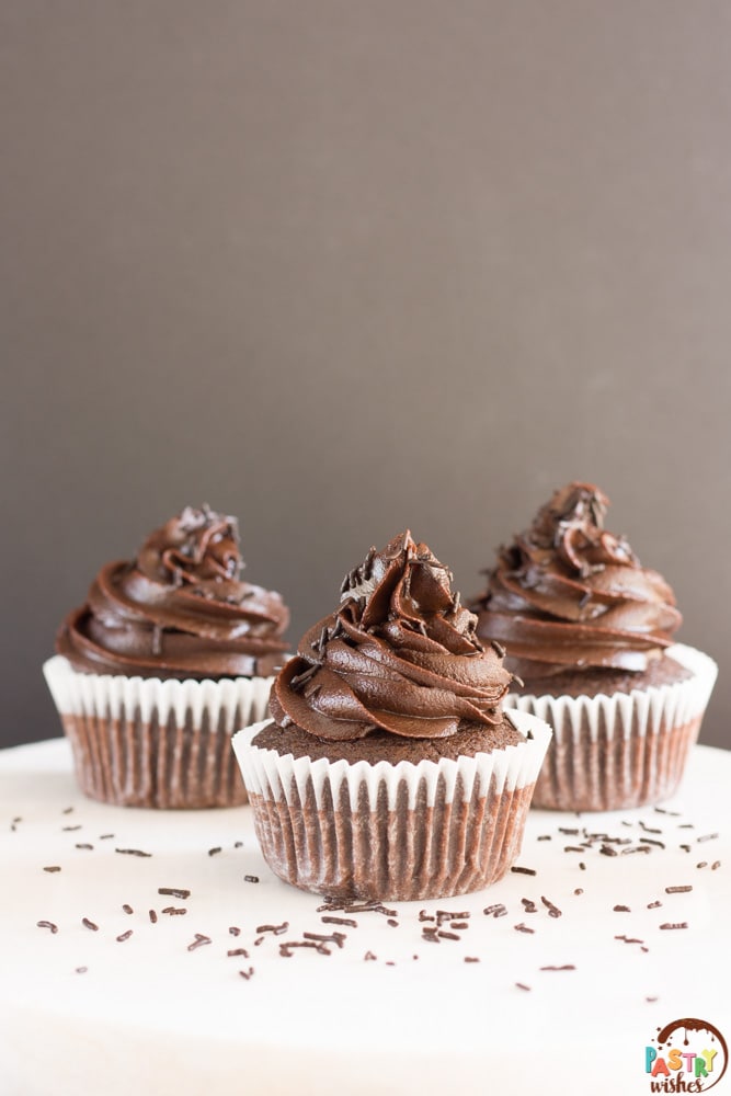 three chocolate cupcakes with dark chocolate frosting