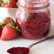 strawberry jam in a jar and on a spoon with strawberries