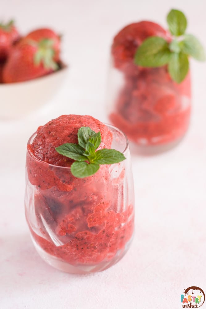 strawberry mint sorbet in two glasses with a bowl of strawberries in the background