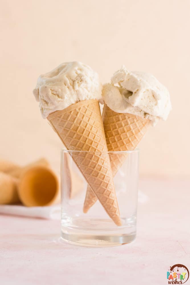 no churn vanilla ice cream on two cones inside a glass with ice cream cones in the background