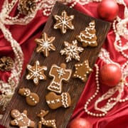 greek gingerbread cookies on a wooden tray surrounded by christmas decorations on a red satin cloth