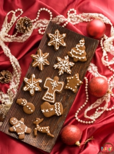 greek gingerbread cookies on a wooden tray surrounded by christmas decorations on a red satin cloth