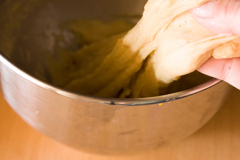 fully kneaded tsoureki dough being pulled from bowl