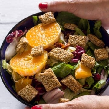 two hands holding a bowl of Greek pasteli salad