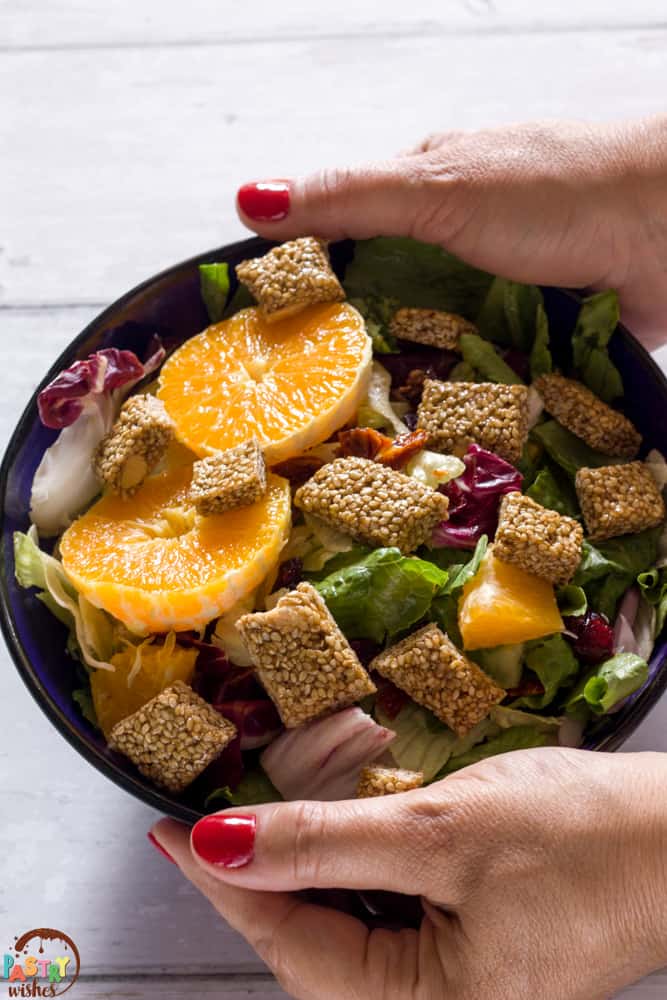 two hands holding a bowl of Greek pasteli salad
