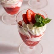 3 strawberry cups with a sprig of mint on a white surface