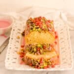 lemon pomegranate cake sliced with glaze in the background featured