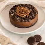 3 ingredient oreo cake on a white plate with oreo cookies and kitchen towel on white surface