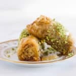 A close up of two baklava rolls on a plate on a white surface.