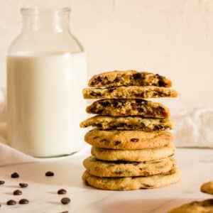 Chocolate chip cookies without brown sugar on a white surface with milk in the background.