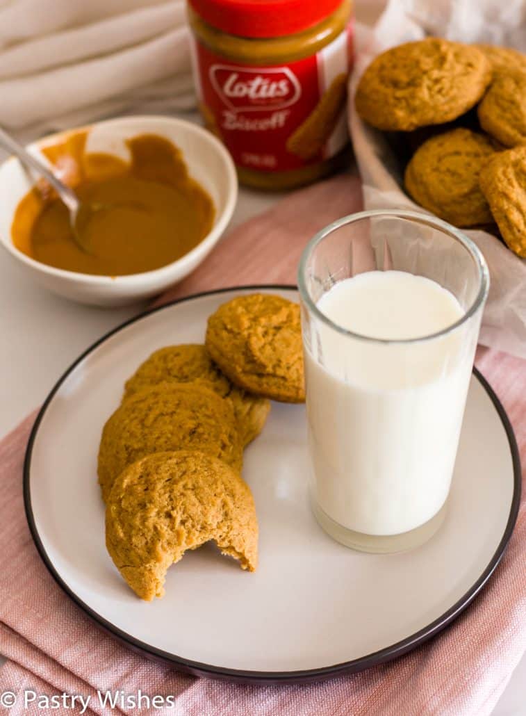 a plate of biscoff butter cookies with a glass of milk and biscoff spread and cookies in the background