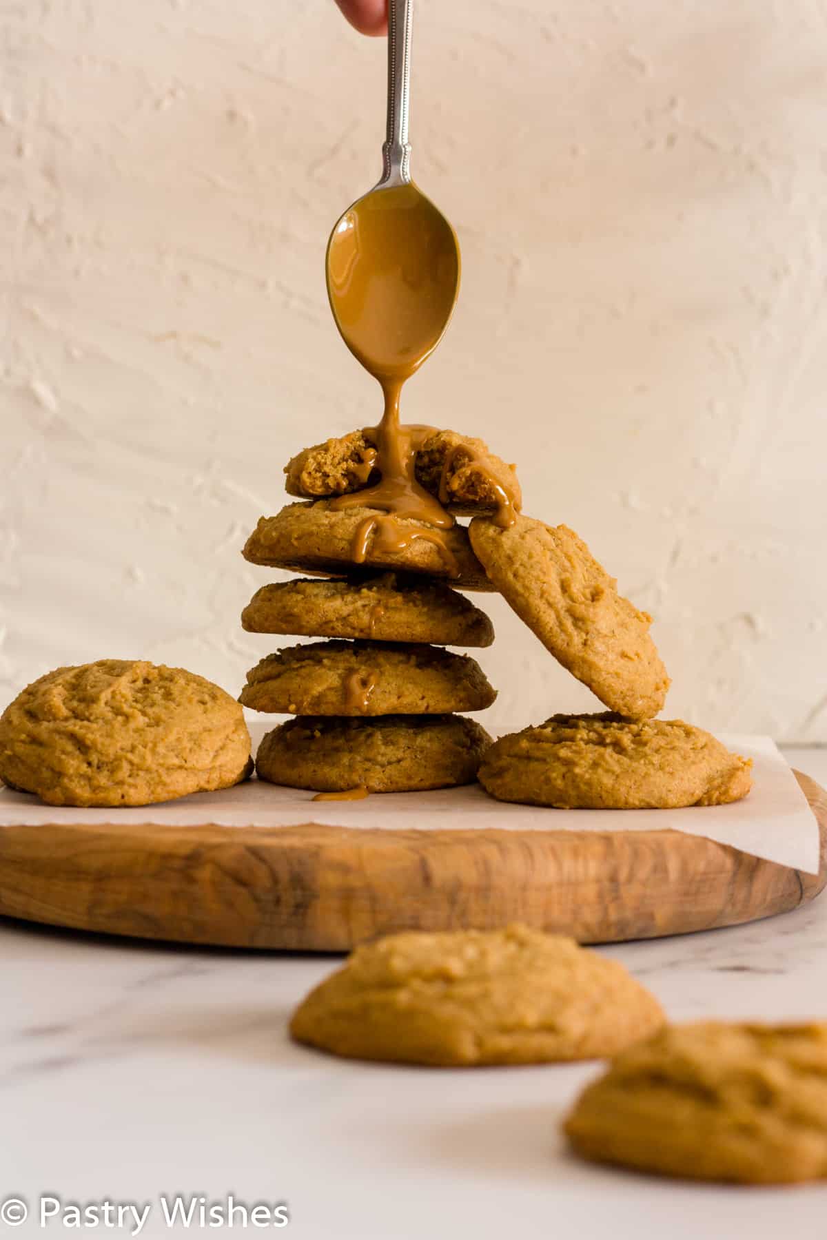 stack of biscoff butter cookies with a spoon drizzling biscoff spread on top