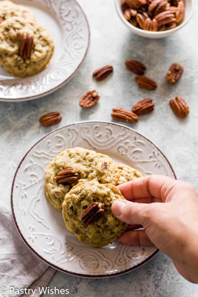 vegan pecan cookies on a plate with pecans and cookies in the background