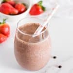 Strawberry banana chocolate smoothie in a glass with a straw.