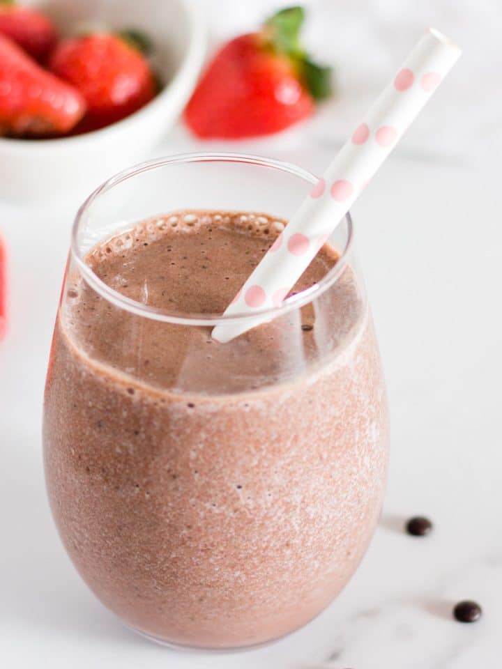 Strawberry banana chocolate smoothie in a glass with a straw.