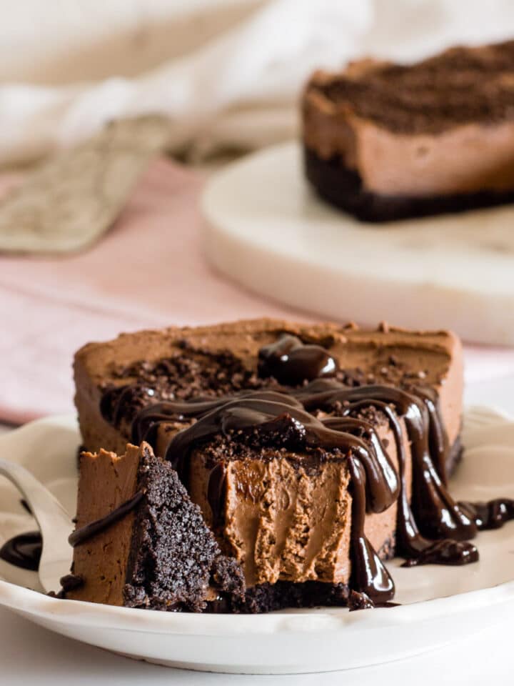 A slice of eggless chocolate cheesecake on a plate with a fork.