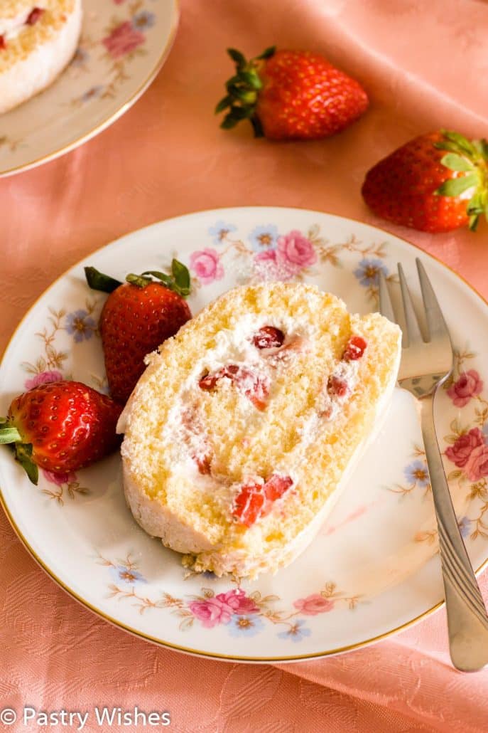 a slice of vanilla swiss roll cake with fresh strawberries