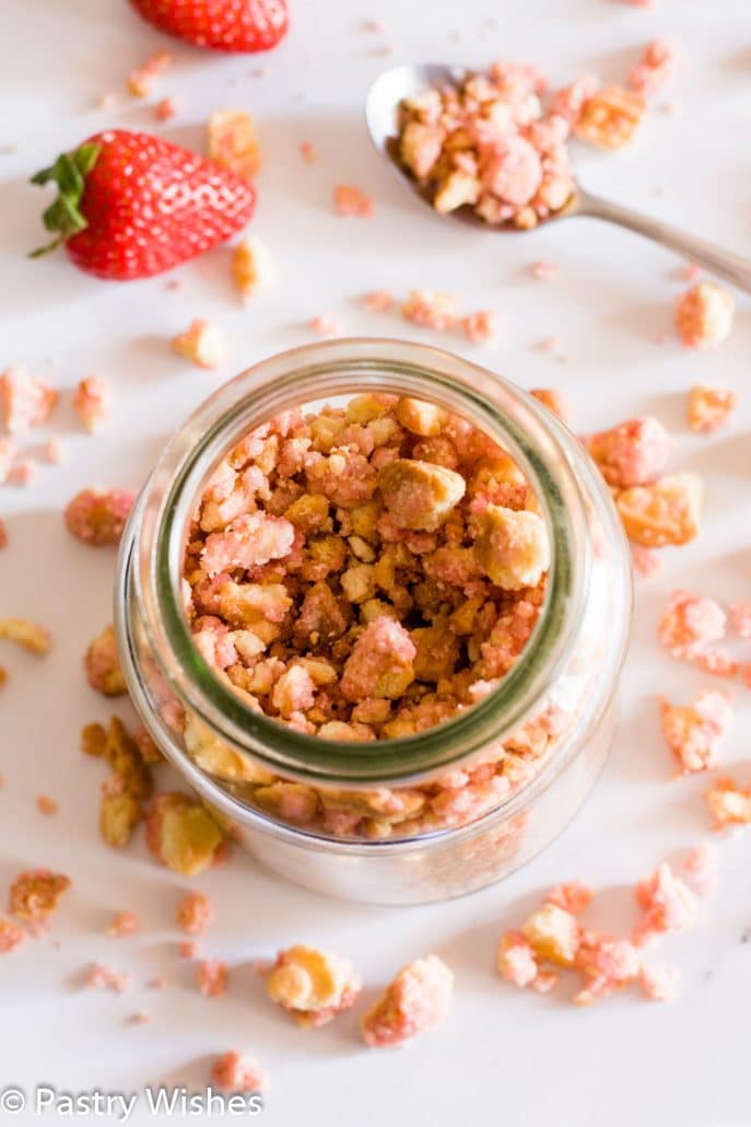strawberry crunch topping in a jar on a white surface