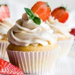 A close up of strawberry filled cupcakes decorated with strawberries and mint leaves.
