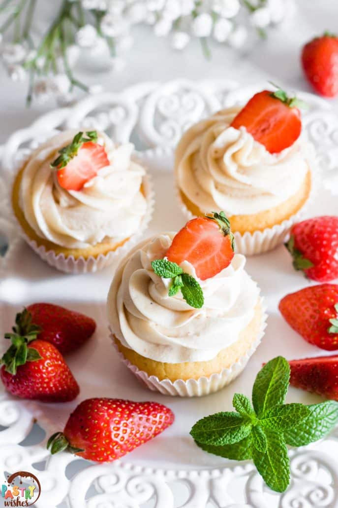 strawberry filled cupcakes decorated with strawberries and mint leaves on a white plate