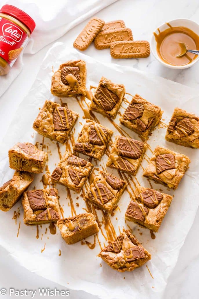 biscoff blondies cut into squares on parchment paper and topped with melted biscoff spread