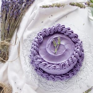 Earl grey lavender cake on a white surface surrounded by lavender flowers.
