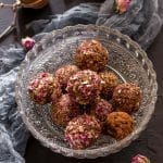 A bowl of rose bliss balls with rose buds in the background.
