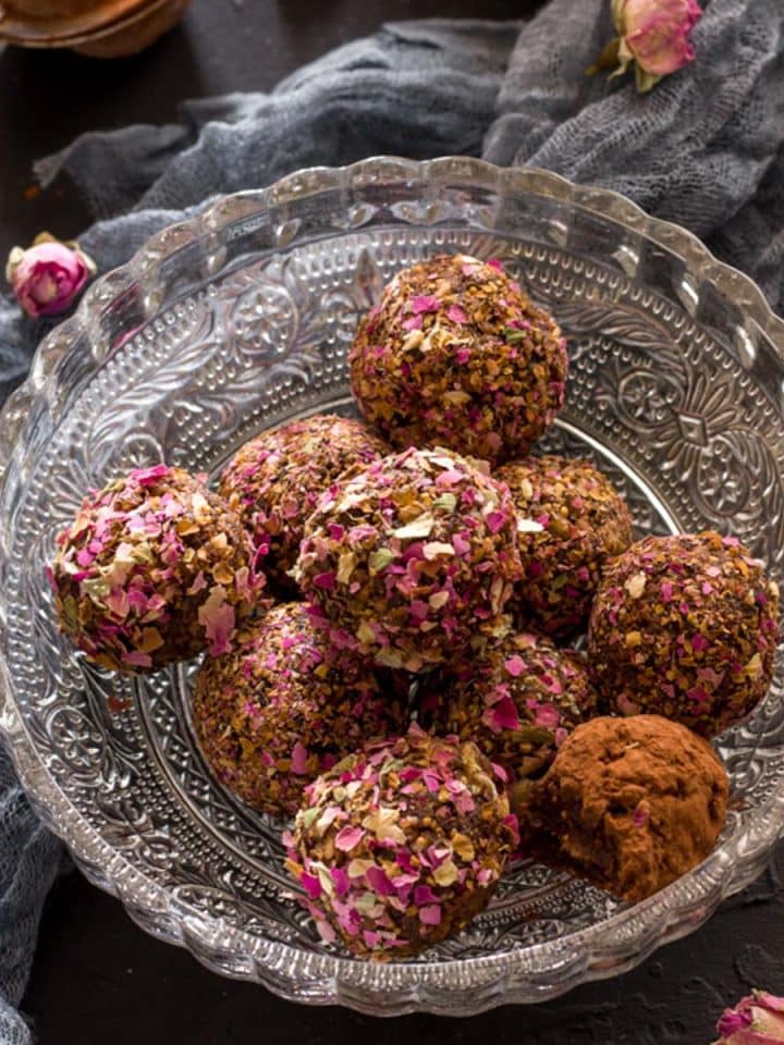 A bowl of rose bliss balls with rose buds in the background.
