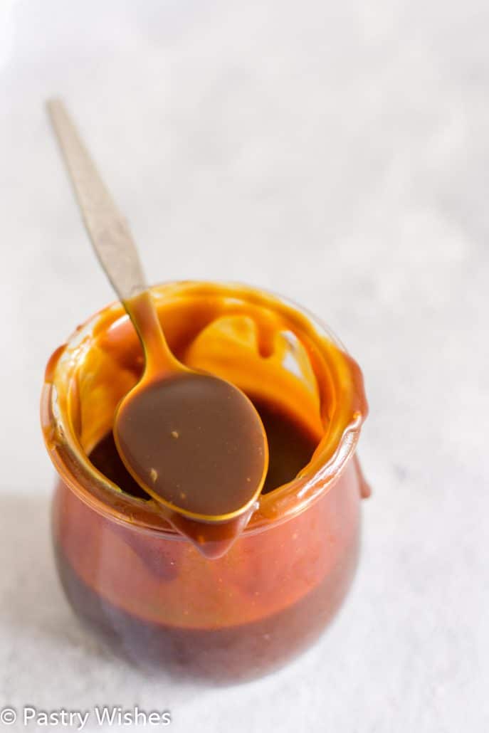 a spoon of salted caramel sauce on top of a jar of caramel