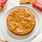 3 ingredient biscoff cake on a white plate with biscoff cookies and spread in the background.