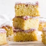Three pieces of coconut and jam cake stacked on top of each other.