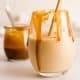 A glass of salted caramel smoothie with a bamboo straw and caramel in the background.
