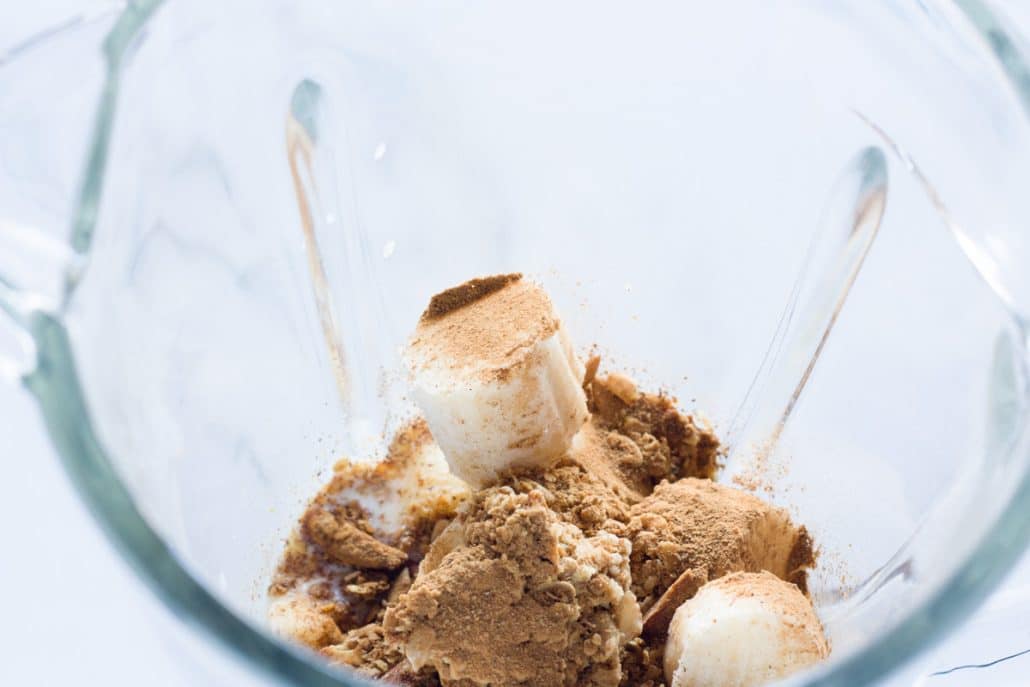 A blender filled with granola smoothie ingredients before blended.