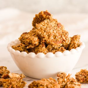 A close up of a white bowl filled with homemade granola clusters.