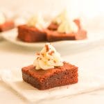 A velvet brownie square on parchment paper topped with cream cheese frosting.