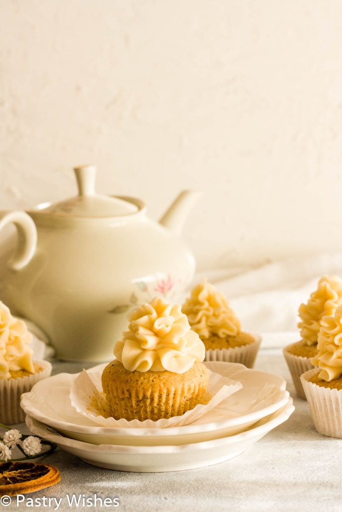 Earl Grey cupcakes on a white surface next to a tea pot.