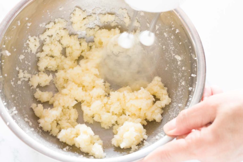 Beating butter and sugar together with a hand mixer.