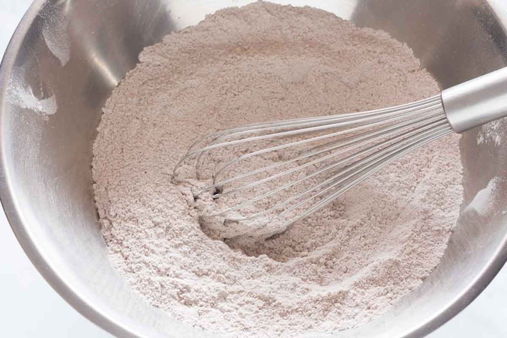 Whisking together flour, leaveners, cocoa powder and salt in a mixing bowl.