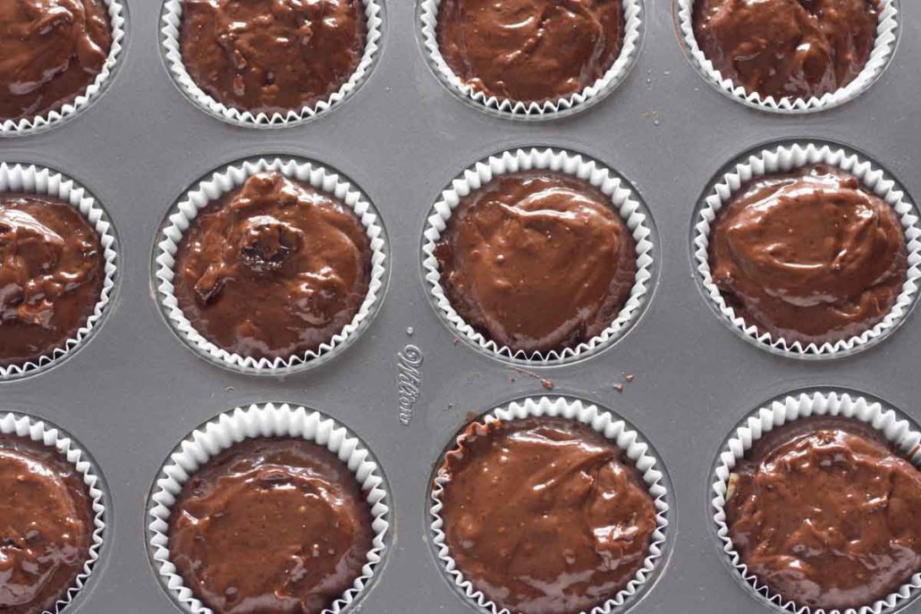 A muffin pan filled with triple chocolate muffin batter.