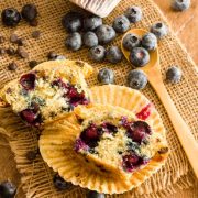 Blueberry chocolate chip muffins on burlap next to blueberries and chocolate chips.