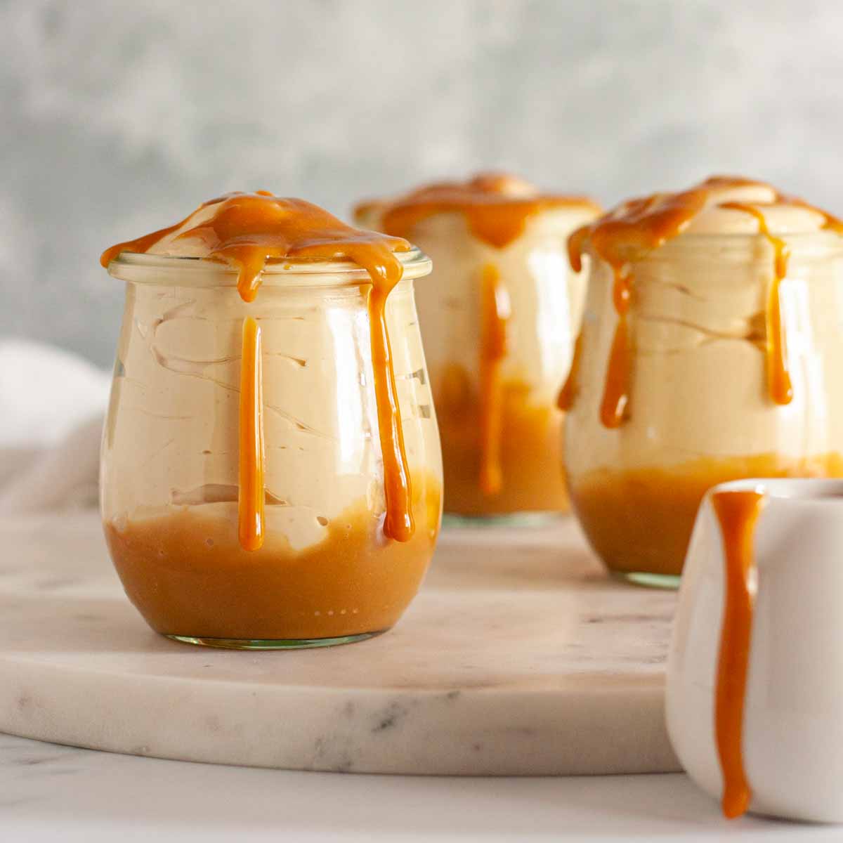 Dulce de leche mousse in three dessert jars and topped with dulce de leche.