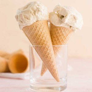 Two ice cream cones with vanilla ice cream in a glass.
