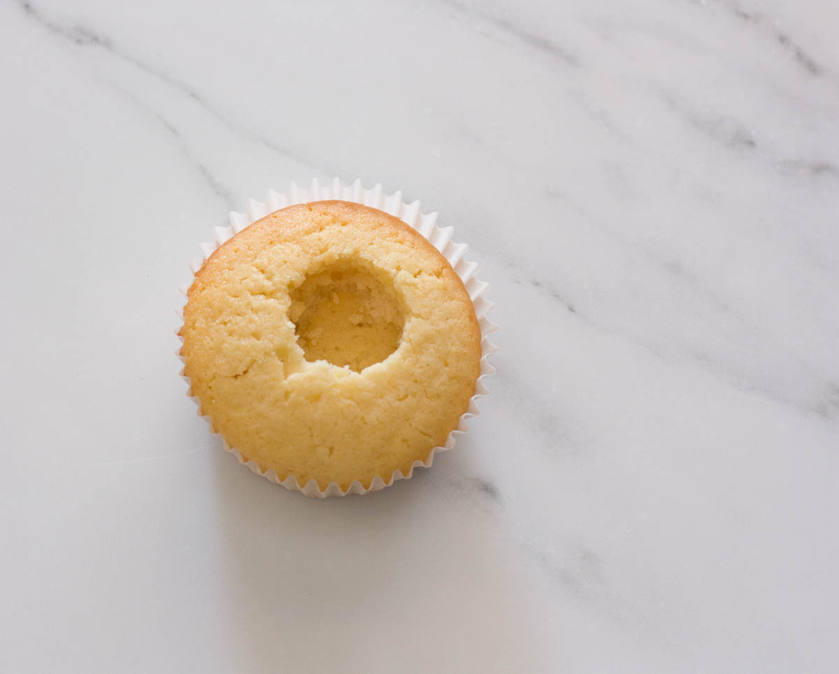 A hollowed out vanilla cupcake on a white surface.