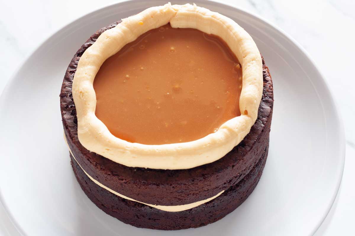 Two chocolate cake layers topped with caramel buttercream frosting and filled with salted caramel sauce.