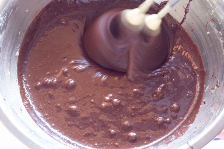 Beating eggs, cocoa mixture and flour mixture with a hand mixer.