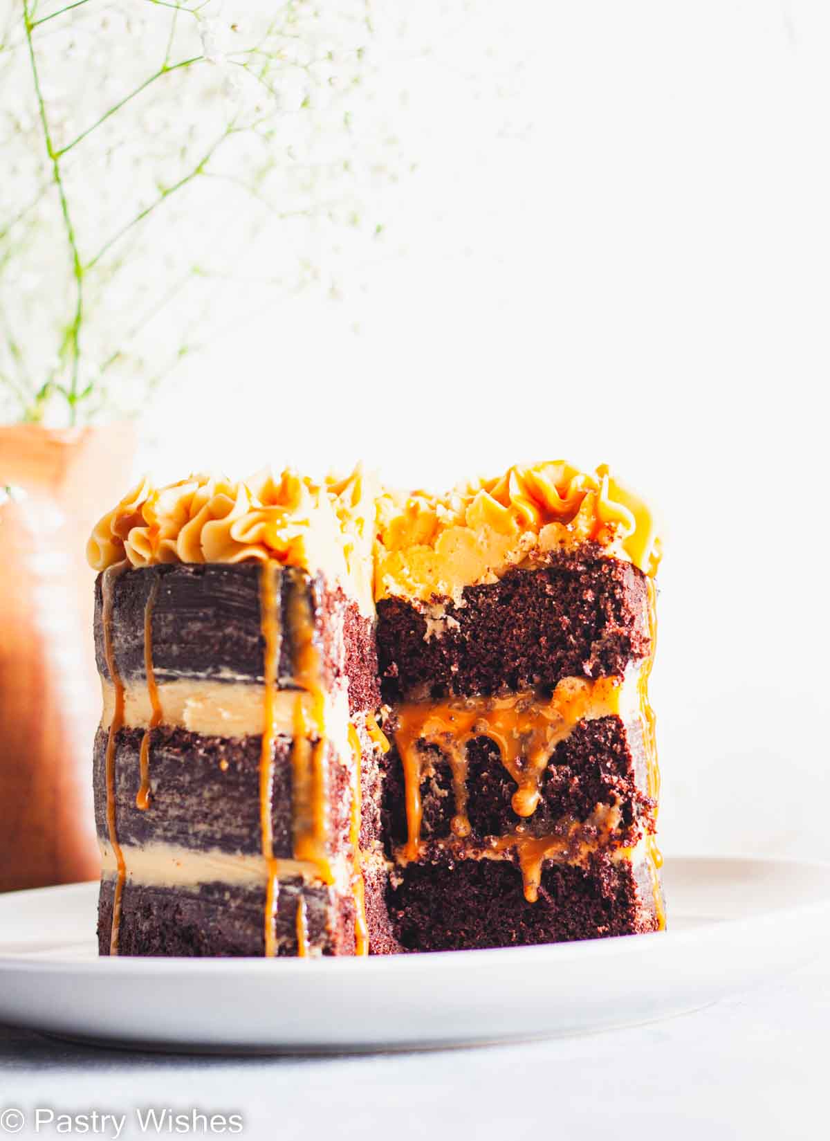 A closeup of a three layer chocolate salted caramel cake with caramel dripping in between the layers.