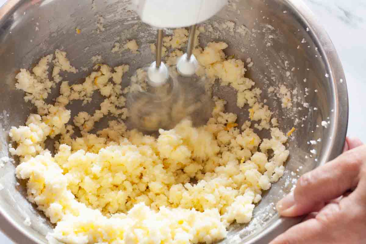 Beating butter with sugar and lemon zest with a hand mixer.