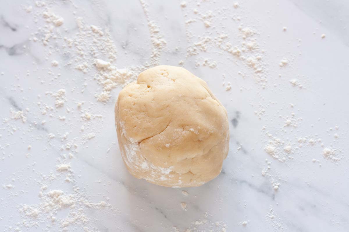 Tart dough shaped into a ball on a floured surface.