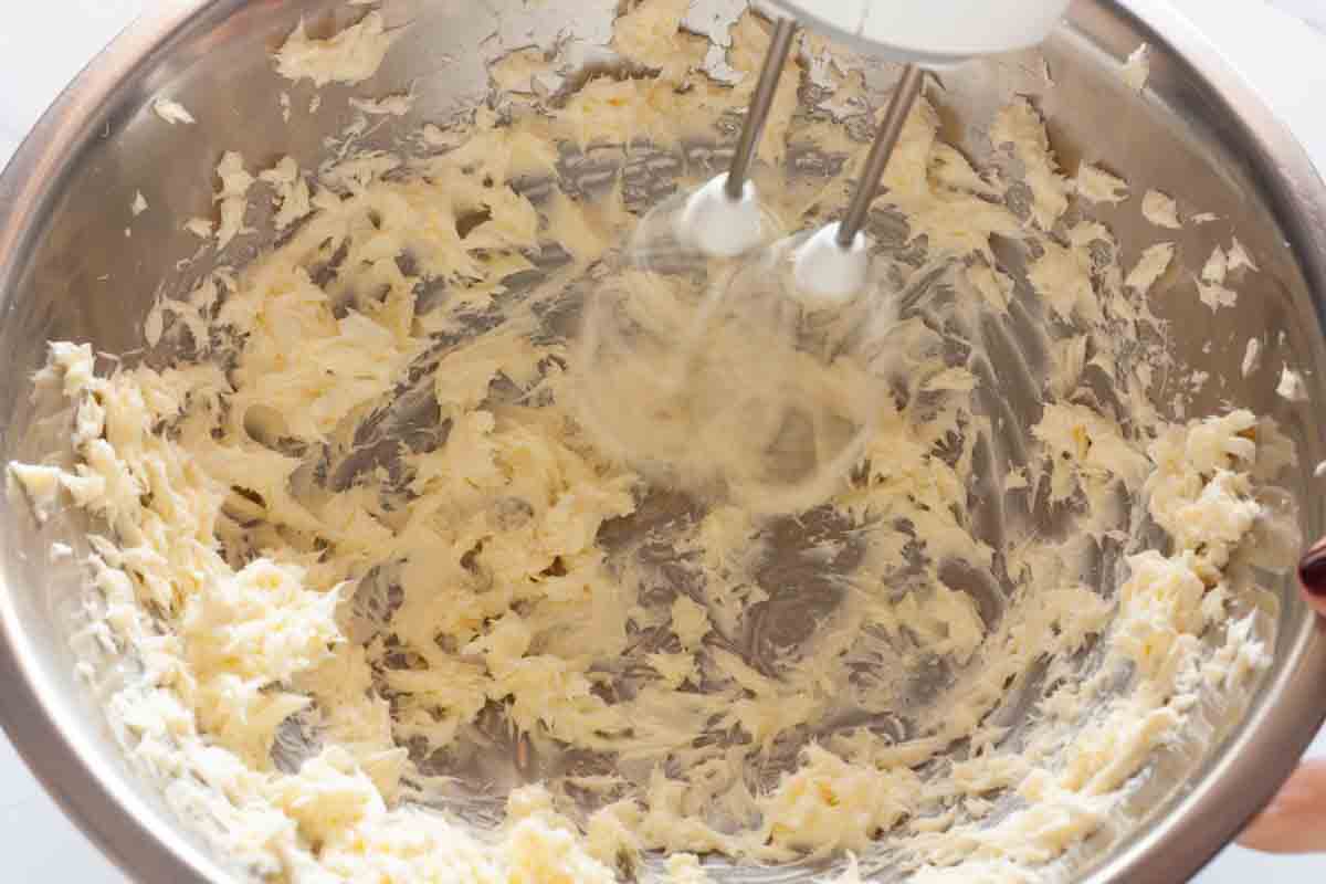 Beating butter in a large mixing bowl with a hand mixer.