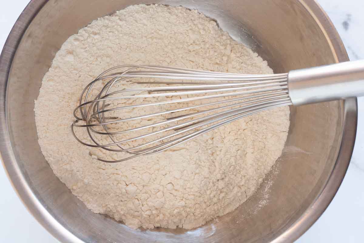 Whisking together flour, baking powder and salt in a metal mixing bowl.